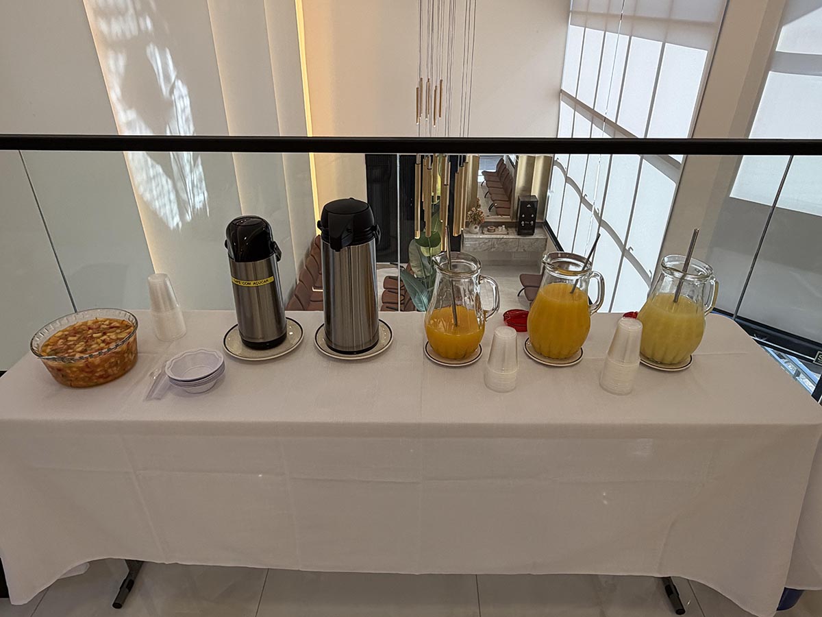 Mesa com café, sucos e salada de frutas no mezanino